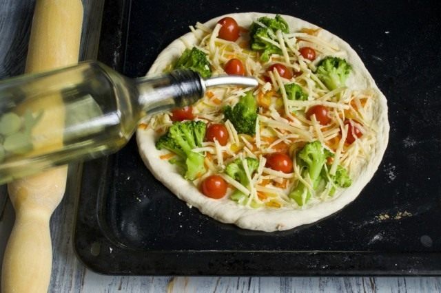 Поливаем пиццу растительным маслом и ставим выпекаться