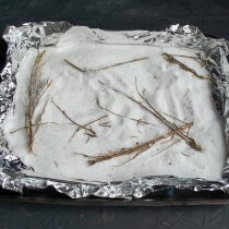 На противень кладём фольгу, на фольгу высыпаем соль, кладём веточки розмарина без листьев На противень кладём фольгу, на фольгу высыпаем соль, кладём веточки розмарина без листьев
