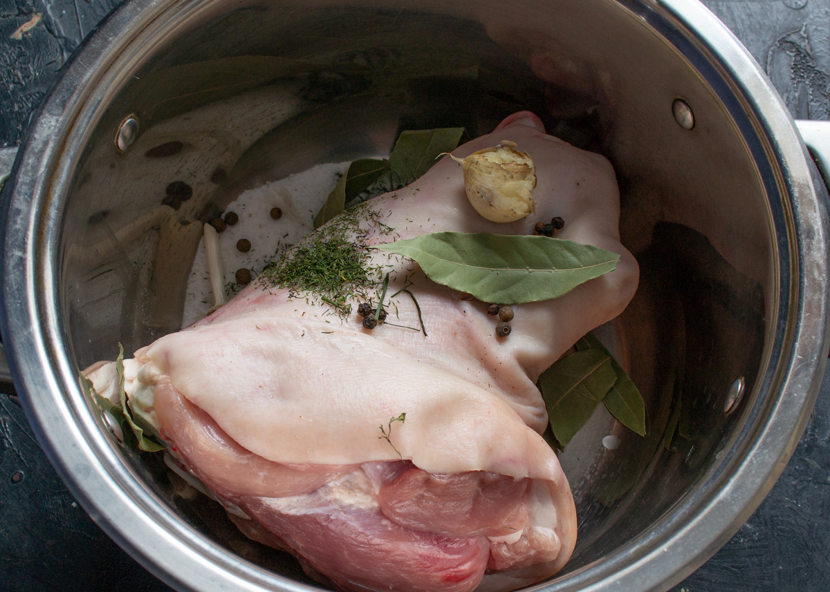 В 5-литровую кастрюлю кладём свиную рульку, добавляем специи и чеснок